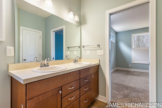 full bathroom with baseboards, double vanity, and a sink