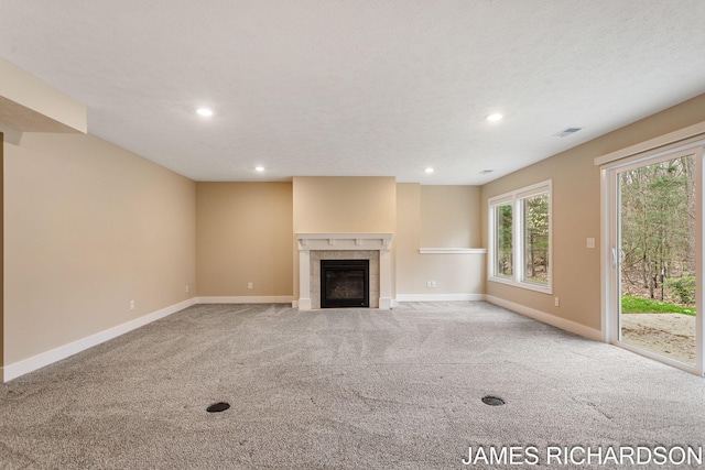 unfurnished living room with carpet flooring, a tile fireplace, visible vents, and baseboards