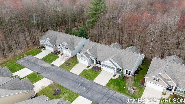 drone / aerial view featuring a wooded view and a residential view