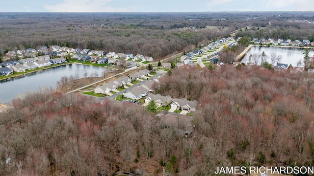 drone / aerial view with a water view, a residential view, and a forest view