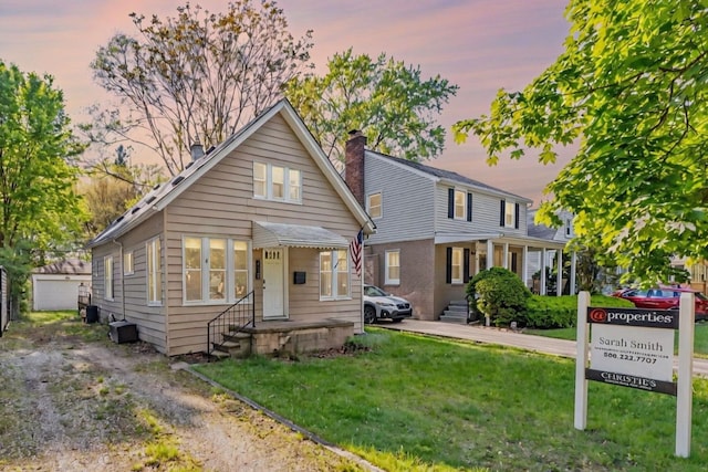 view of front of property with a yard, an outdoor structure, and entry steps