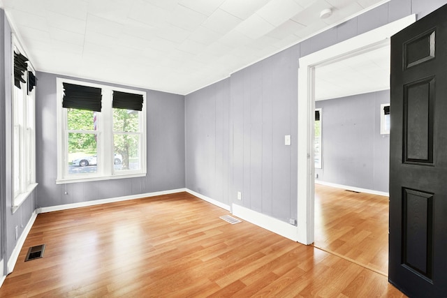 unfurnished room featuring healthy amount of natural light, light wood-type flooring, and baseboards
