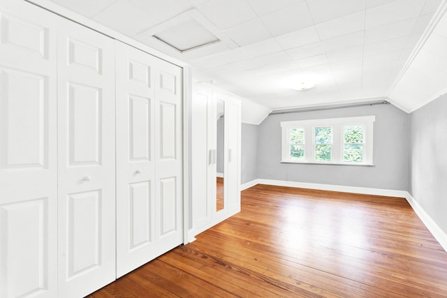 unfurnished bedroom with vaulted ceiling, a closet, wood finished floors, and baseboards