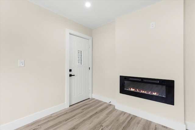 foyer featuring recessed lighting, baseboards, a glass covered fireplace, and wood finished floors
