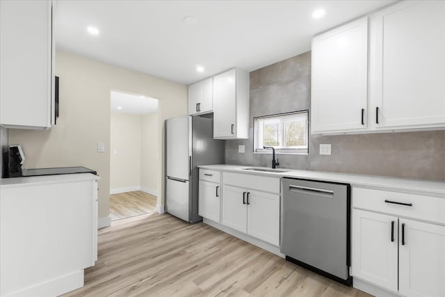 kitchen with light countertops, stainless steel appliances, white cabinetry, and a sink
