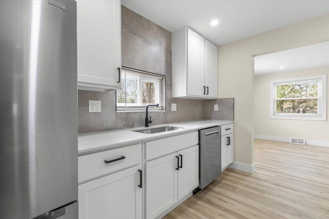 kitchen featuring appliances with stainless steel finishes, a sink, light countertops, white cabinetry, and visible vents