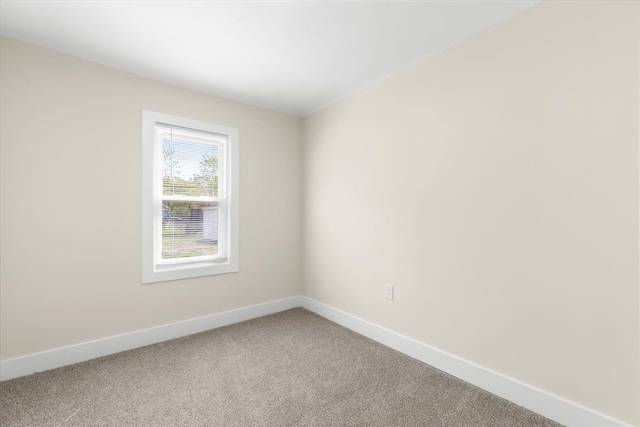spare room with baseboards and light carpet