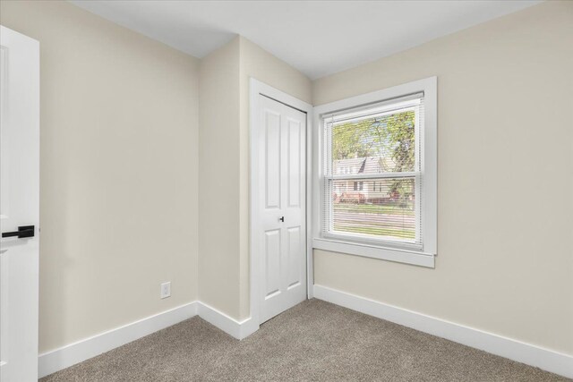carpeted empty room featuring baseboards