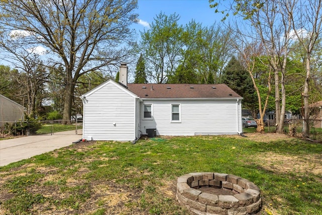 back of house with fence, a shingled roof, a chimney, a yard, and a fire pit