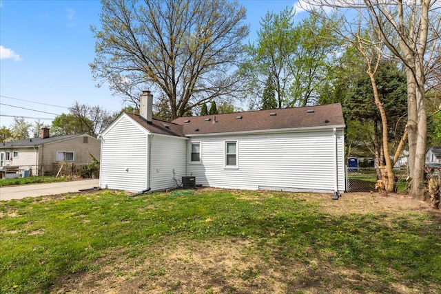 back of house with a lawn, fence, a chimney, and central AC unit