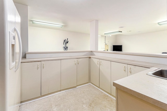 kitchen with light countertops, light tile patterned floors, and white refrigerator with ice dispenser