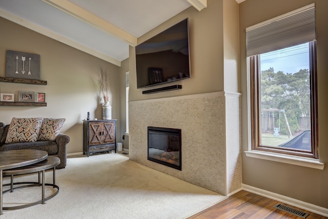 sitting room with a healthy amount of sunlight, lofted ceiling with beams, wood finished floors, and visible vents