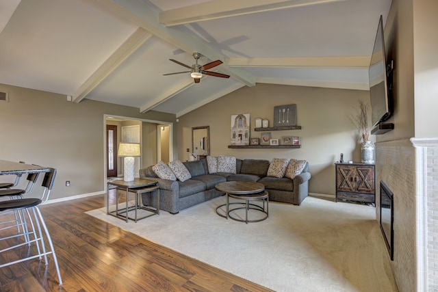 living area with visible vents, wood finished floors, baseboards, ceiling fan, and vaulted ceiling with beams