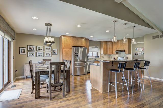 kitchen with a kitchen breakfast bar, visible vents, baseboards, stainless steel appliances, and dark wood-type flooring