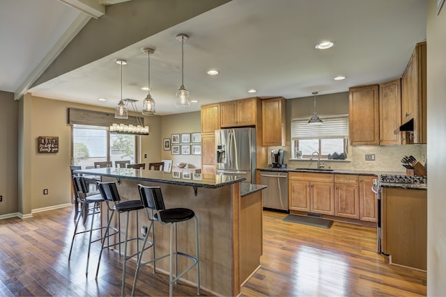 kitchen with appliances with stainless steel finishes, a sink, a breakfast bar area, recessed lighting, and a kitchen island