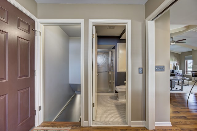interior space featuring ceiling fan, toilet, baseboards, wood finished floors, and a stall shower