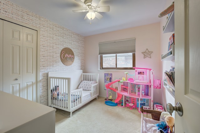 bedroom with carpet floors, a ceiling fan, a closet, and a nursery area