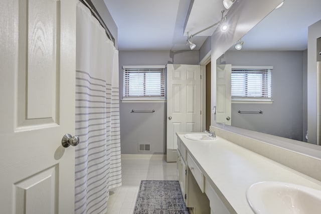 bathroom with visible vents, a sink, tile patterned flooring, and double vanity