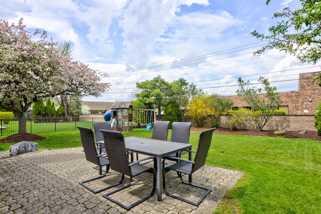 view of patio with a playground, outdoor dining space, and a fenced backyard
