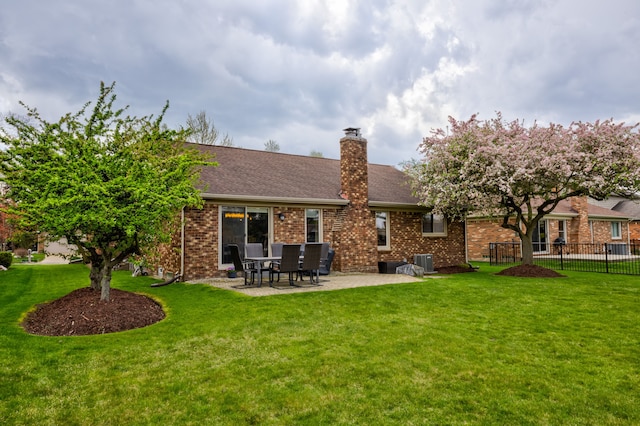rear view of house featuring a patio, a lawn, fence, and brick siding