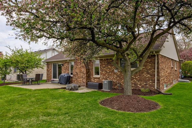 back of house featuring brick siding, a patio, a lawn, and central air condition unit