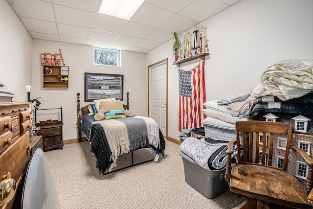 carpeted bedroom with baseboards and a paneled ceiling