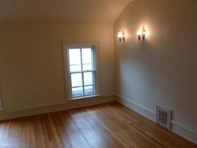 spare room with wood finished floors, visible vents, and baseboards