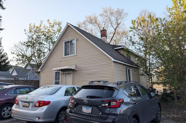 view of property exterior featuring fence, a chimney, and a shingled roof