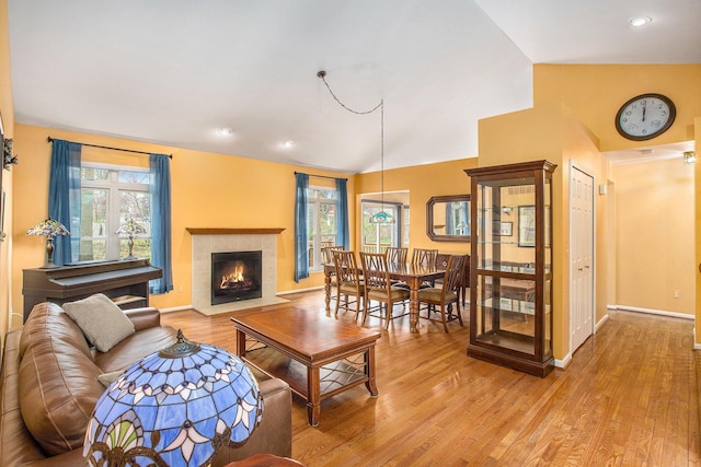 living room featuring recessed lighting, a fireplace, light wood-style floors, vaulted ceiling, and baseboards