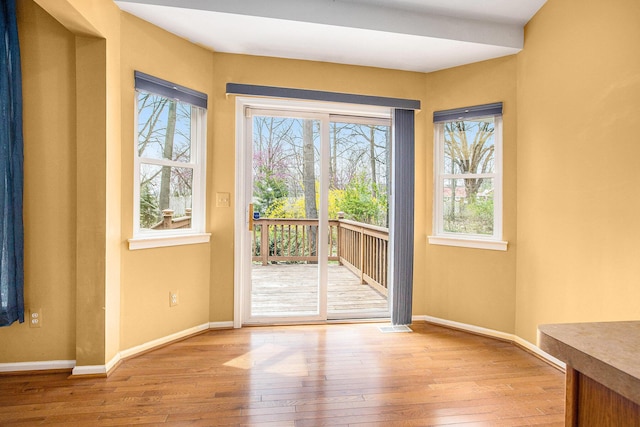 doorway with baseboards, visible vents, wood-type flooring, and plenty of natural light