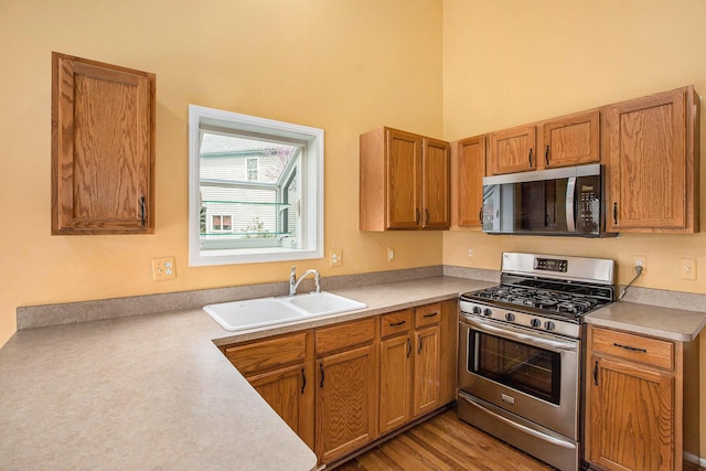 kitchen with brown cabinets, a sink, stainless steel appliances, light countertops, and a towering ceiling