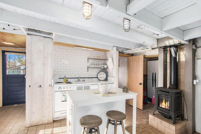 350 Ferry St, Douglas, MI 49406 - kitchen featuring a breakfast bar area, tasteful backsplash, open shelves, a wood stove, and light countertops