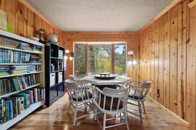 320 Marble St, Cadillac, MI 49601 - dining space featuring ornamental molding, baseboards, wooden walls, a textured ceiling, and light wood-style flooring