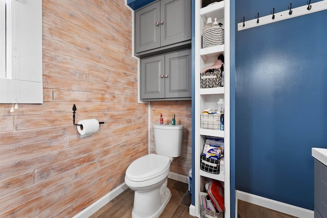 320 Marble St, Cadillac, MI 49601 - bathroom with wooden walls, baseboards, toilet, and wood finished floors