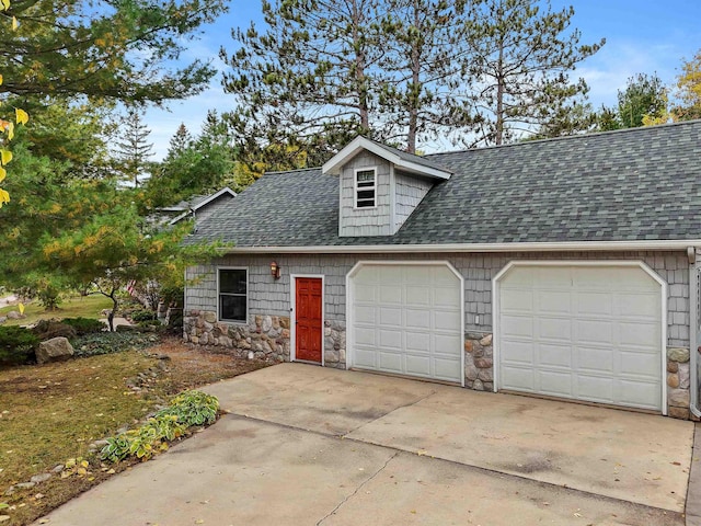 320 Marble St, Cadillac, MI 49601 - view of front facade with concrete driveway, an attached garage, a shingled roof, and stone siding
