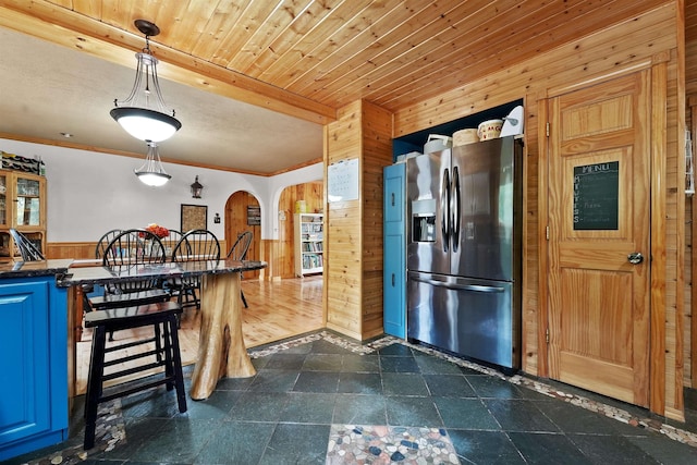 320 Marble St, Cadillac, MI 49601 - kitchen featuring wooden walls, dark countertops, stainless steel fridge, arched walkways, and blue cabinets