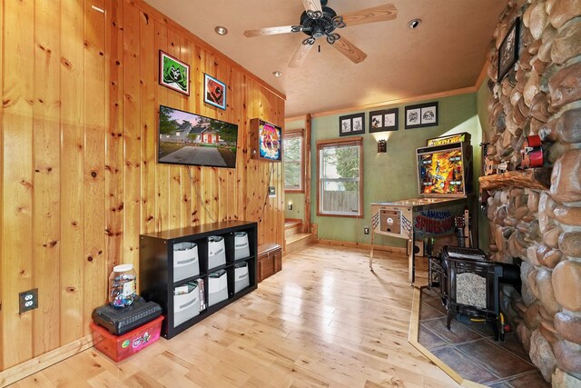 320 Marble St, Cadillac, MI 49601 - interior space featuring a wood stove, ceiling fan, wood finished floors, and wood walls
