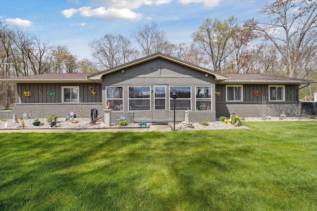 back of property featuring roof with shingles, board and batten siding, a yard, and brick siding