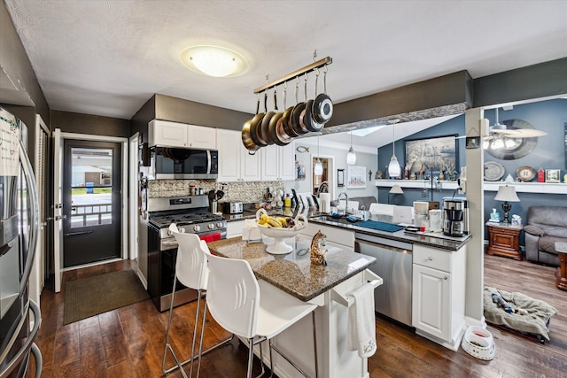 kitchen with dark wood-style flooring, stainless steel appliances, white cabinetry, and tasteful backsplash