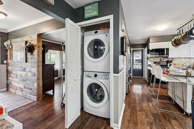 laundry room featuring laundry area, ornamental molding, stacked washer / dryer, baseboards, and dark wood finished floors