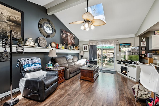 living area with lofted ceiling with beams, a ceiling fan, a warm lit fireplace, and wood finished floors