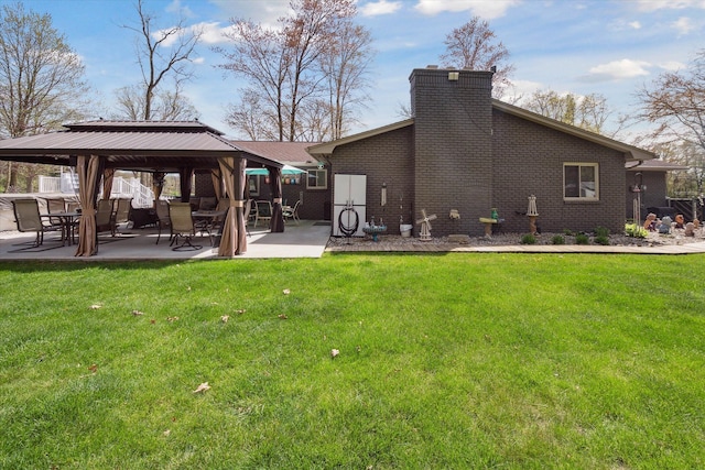 rear view of property featuring a yard, brick siding, a gazebo, and a chimney