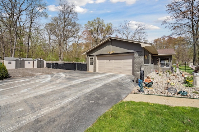 exterior space featuring an outdoor structure, a garage, aphalt driveway, fence, and a storage shed