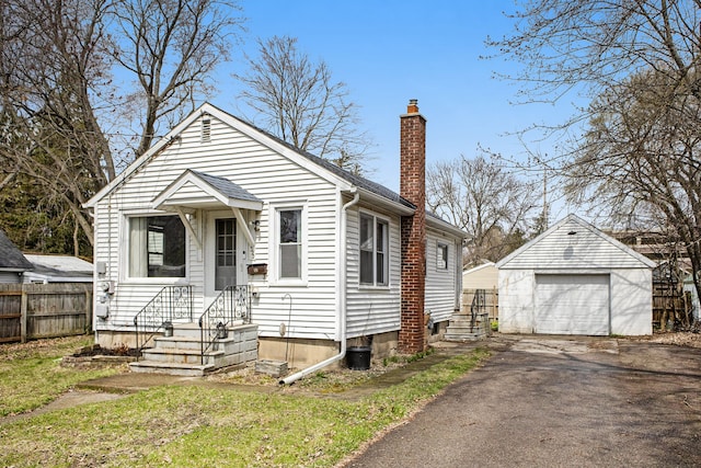 322 Astor Ave, Lansing, MI 48910 - view of front of house with a chimney, fence, an outdoor structure, asphalt driveway, and a garage