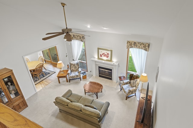 carpeted living area featuring a ceiling fan, vaulted ceiling, and a tiled fireplace