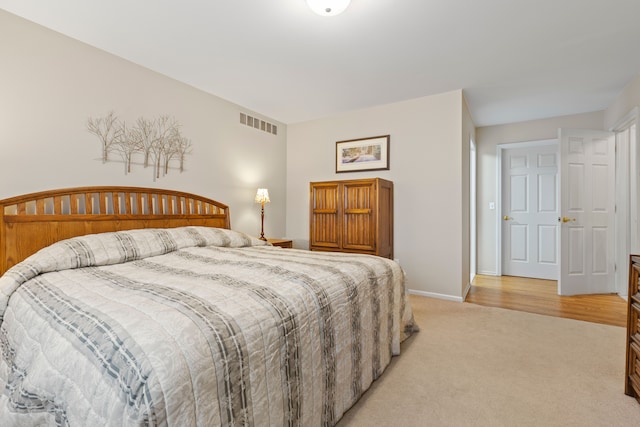 bedroom featuring baseboards, light colored carpet, and visible vents