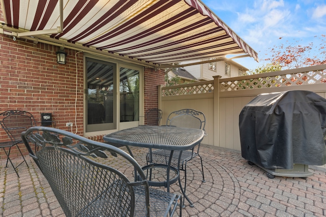 view of patio featuring fence, outdoor dining space, and a grill
