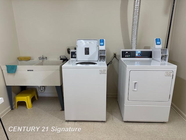 clothes washing area with separate washer and dryer, a sink, and baseboards