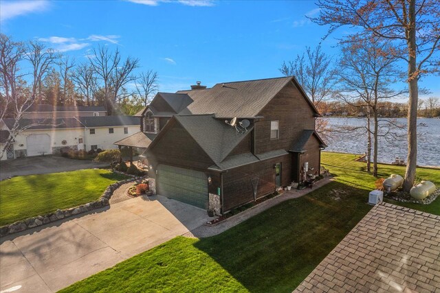 view of home's exterior featuring driveway, a chimney, a lawn, a water view, and stone siding
