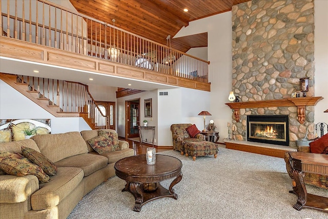 living room with wood ceiling, a stone fireplace, stairs, and high vaulted ceiling